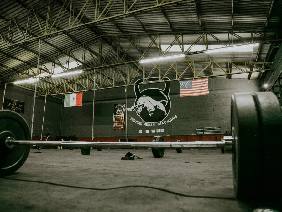 Sala amplia con barras olímpicas y discos apoyados en el piso