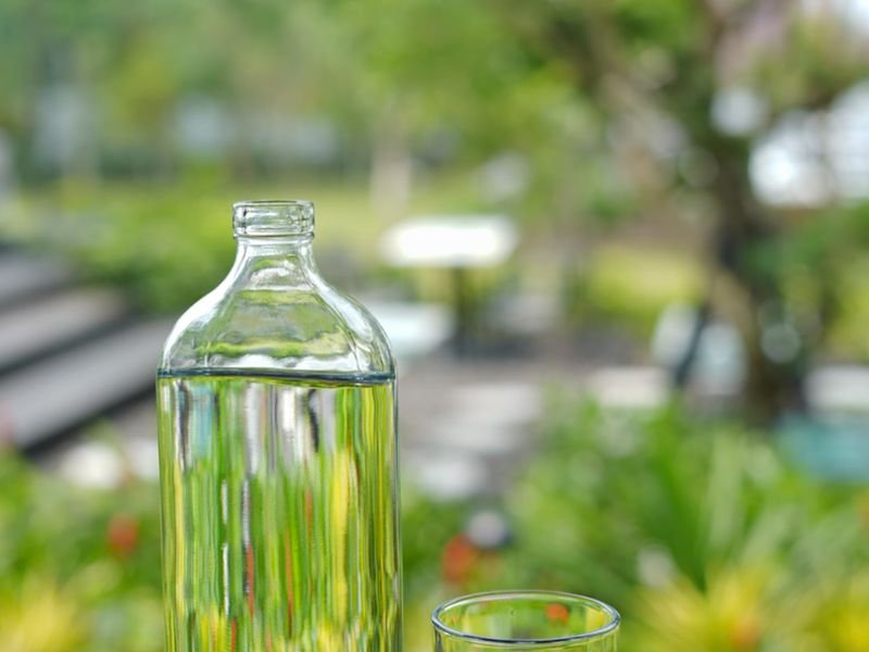 Botella de agua con vaso servido sobre la mesa
