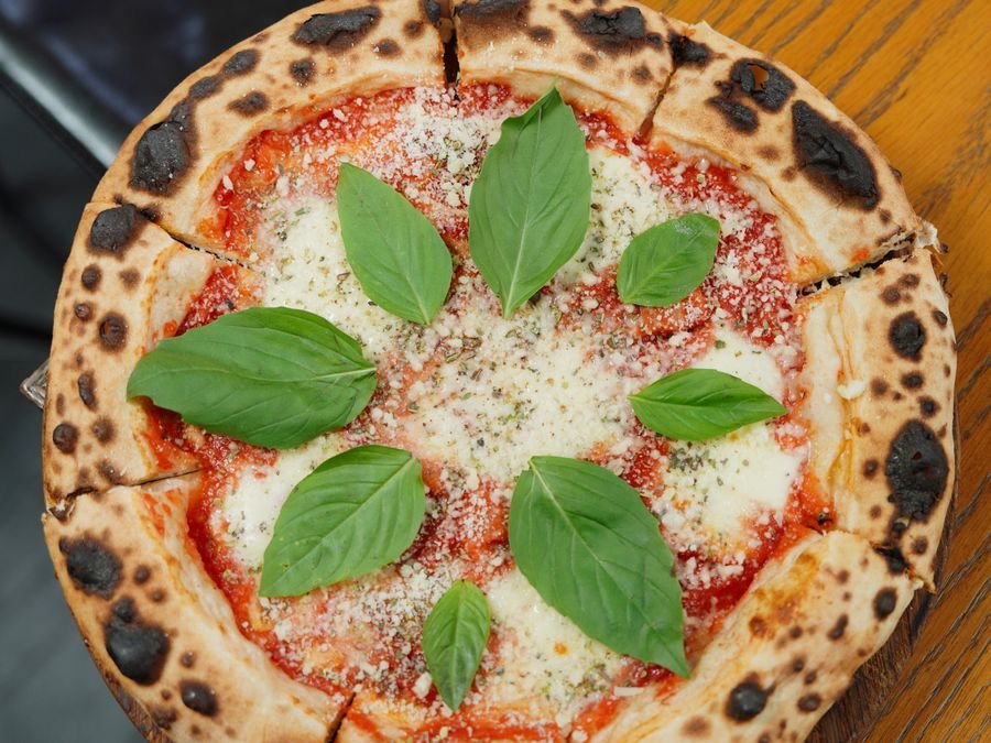 Pizza recién salida del horno a leña con albahaca fresca