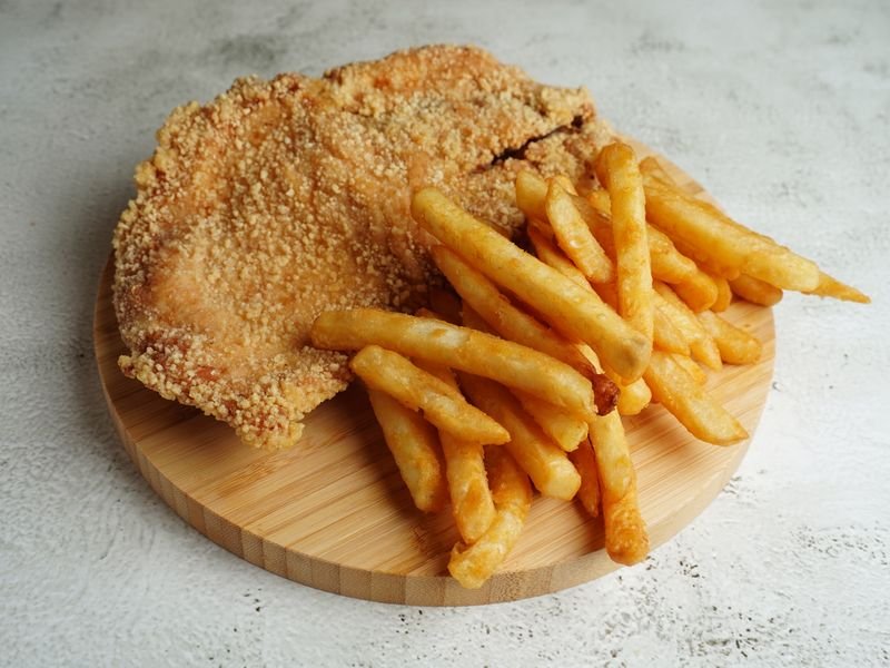 Milanesa crocante con papas fritas sobre tabla