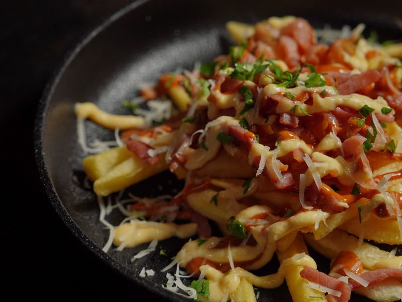 Papas fritas con cheddar derretido y panceta crocante