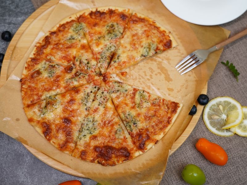 Pizza de muzzarella al molde cortada en porciones sobre tabla de madera