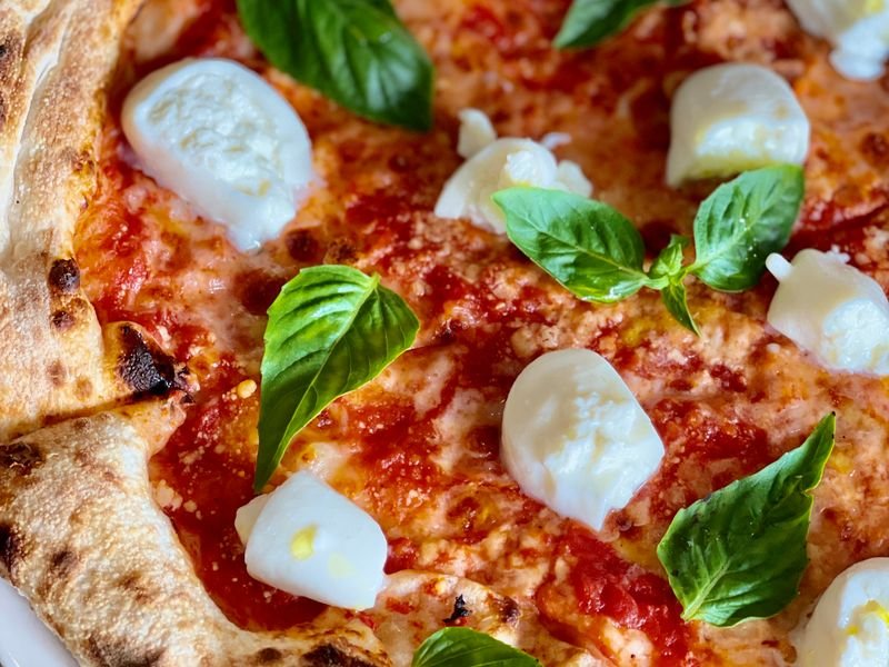 Pizza napolitana con rodajas de tomate fresco y albahaca