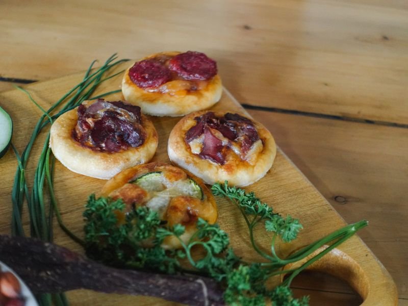 Pizzetas con carne y fiambre sobre tabla de madera